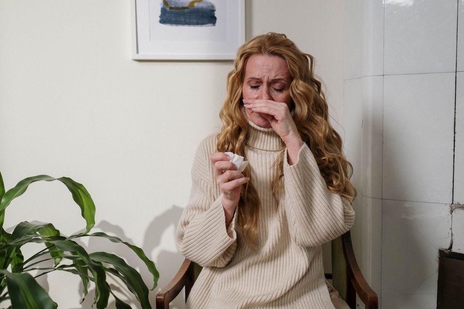 Femme se mouchant à l'intérieur, symptôme courant du rhume comme de l'allergie