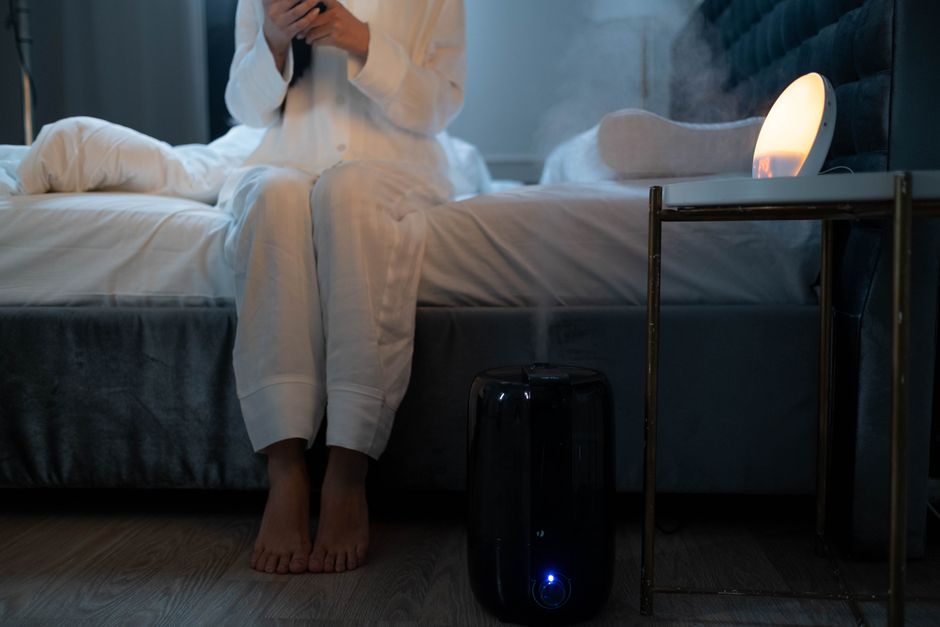 Un humidificateur diffuse une fine brume dans une chambre à l'ambiance tamisée le soir.