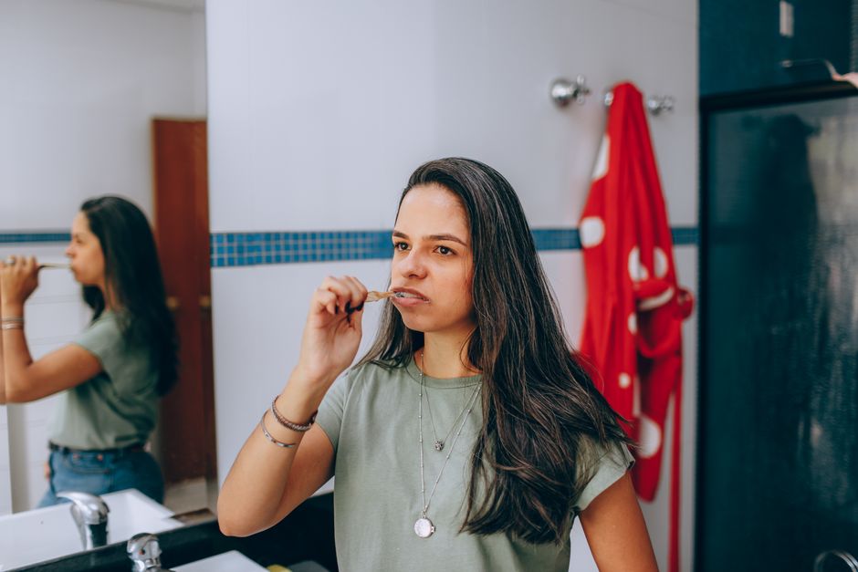 Jeune femme qui se brosse les dents le soir dans sa salle de bain