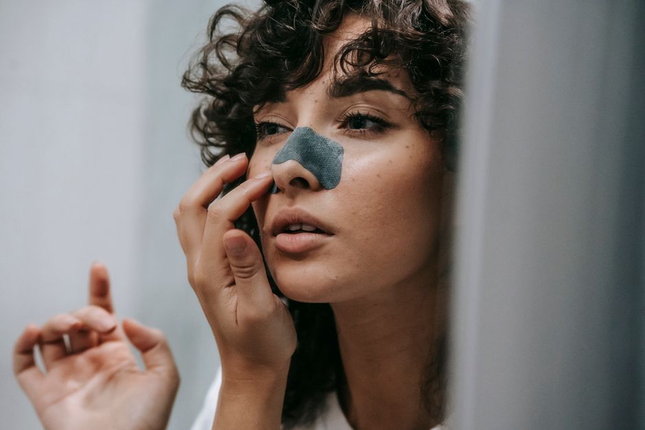 Femme appliquant une bandelette nasale devant le miroir de la salle de bain