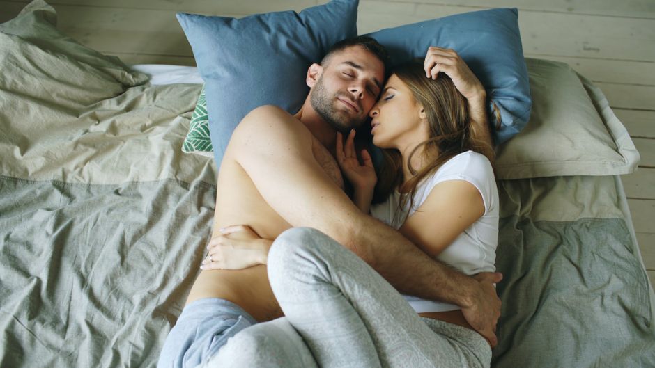 Un couple dans son lit, l'un des deux les yeux ouverts pendant que l'autre dort