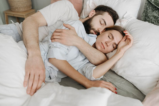 Un couple dans un lit, de nuit, chacun dans sa position de sommeil