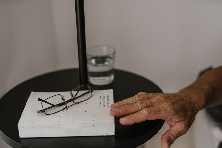 Verre d'eau posé sur une table de nuit à côté d'une lampe, pour s'hydrater en cas de bouche sèche