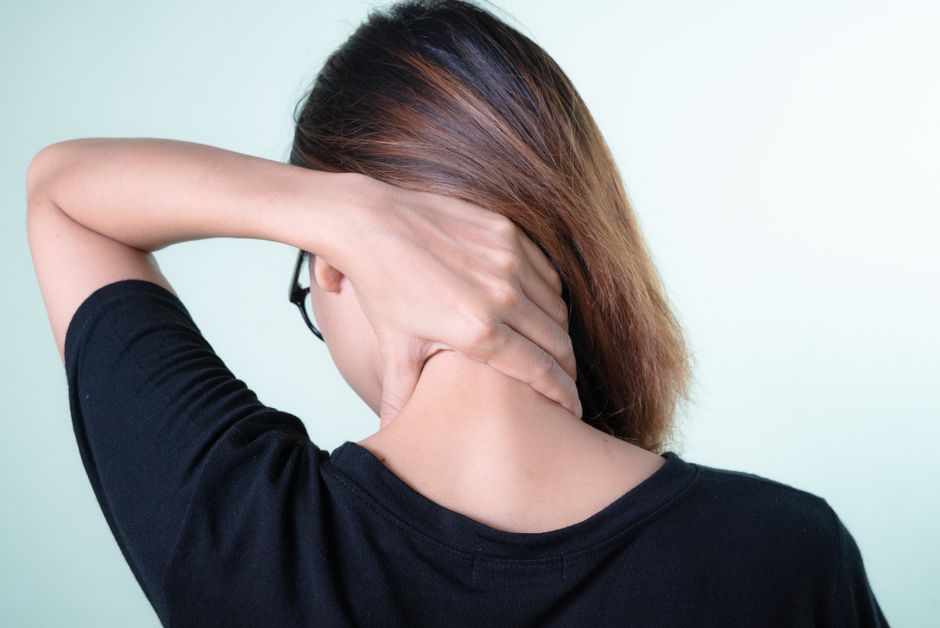 Femme qui masse sa nuque et sa mâchoire, tendues par de mauvaises habitudes posturales de la langue