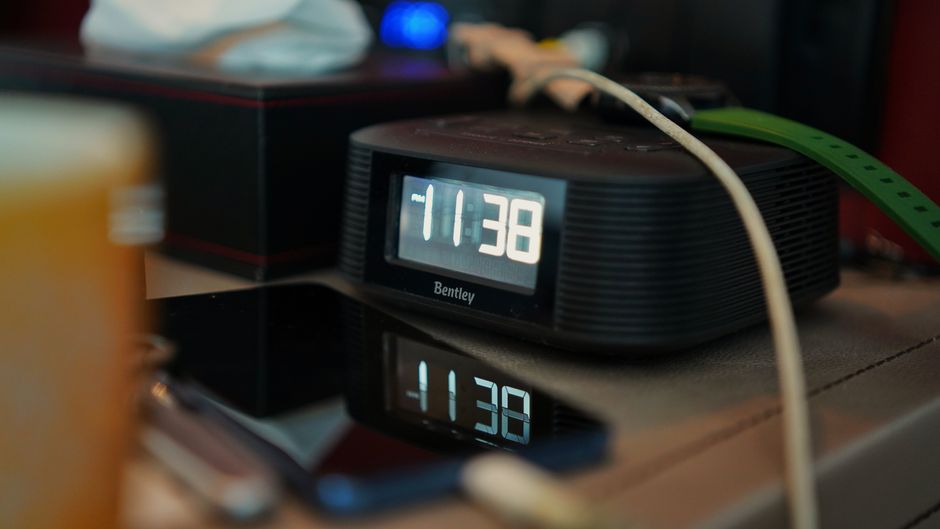 Smartphone allumé sur une table de nuit tard le soir, à côté d'un réveil