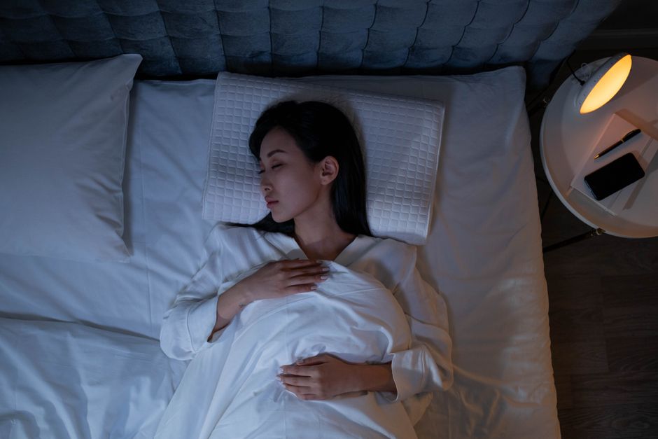 Femme dormant paisiblement dans une pièce sombre, illustrant un sommeil profond et réparateur
