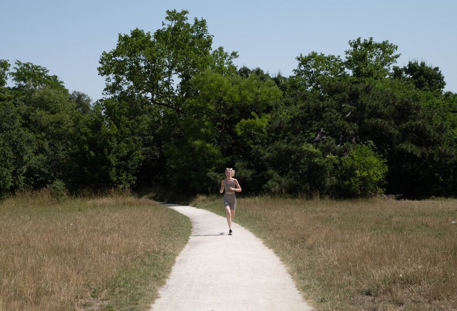 Coureur sur un sentier forestier ensoleillé, en pleine respiration pendant l'effort