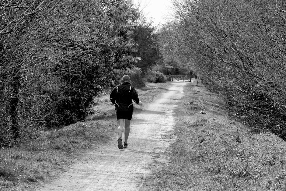 Personne qui reprend la course à pied sur un chemin forestier