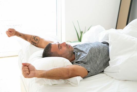 Un jeune homme s'étire dans son lit au réveil, lumière du matin
